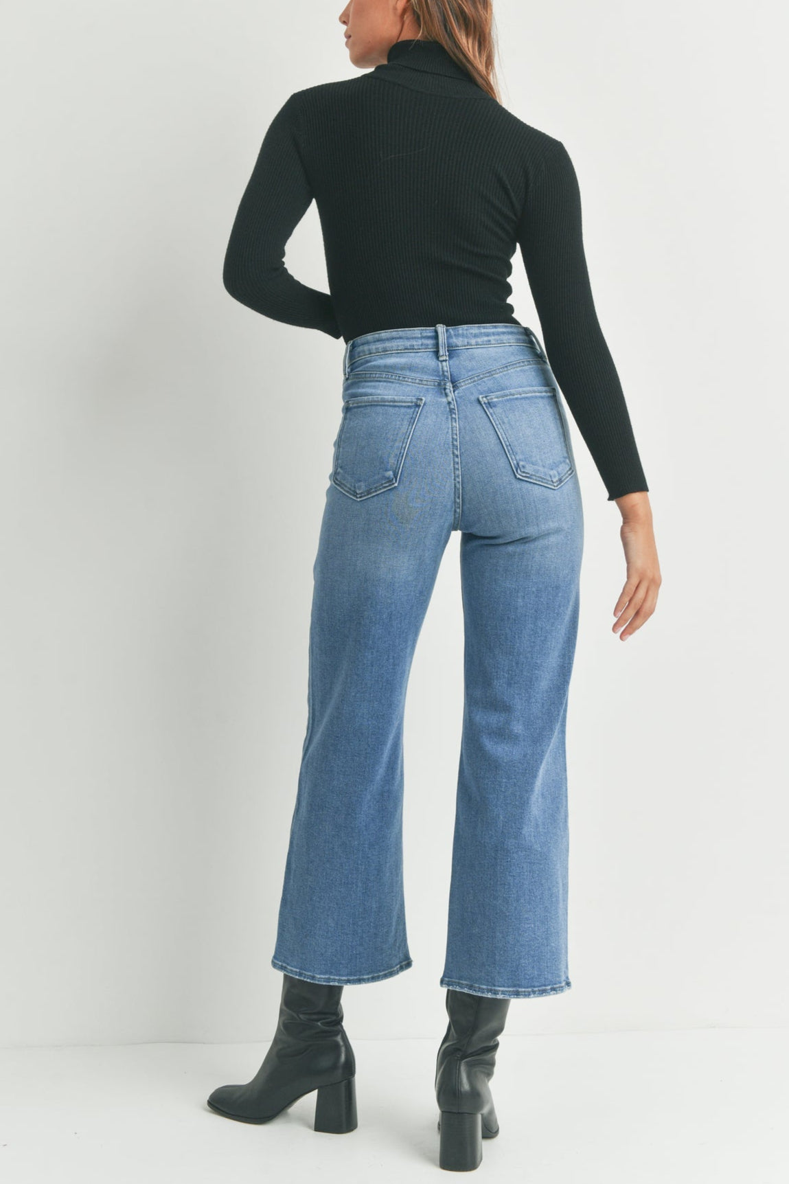Person wearing blue jeans and a black top on a white background