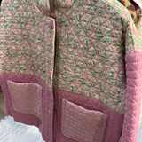 Pink quilted jacket with floral pattern on a hanger