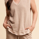 Woman wearing a beige sleeveless top and pants against a beige background