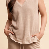 Woman wearing a beige sleeveless top and pants against a beige background