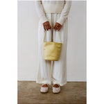 Butter yellow Vancouver bucket bag carried with a white outfit