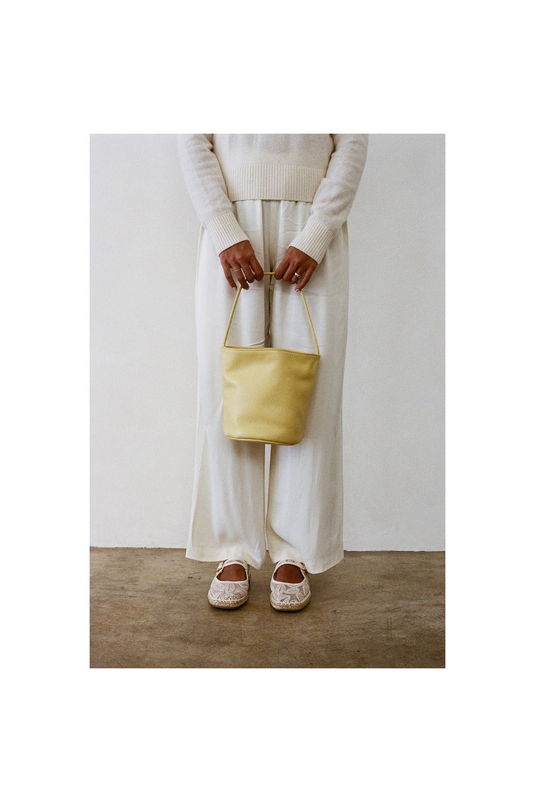 Butter yellow Vancouver bucket bag carried with a white outfit