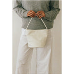 Ivory woven leather bucket bag carried by hand