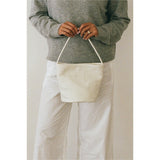 Ivory woven leather bucket bag carried by hand