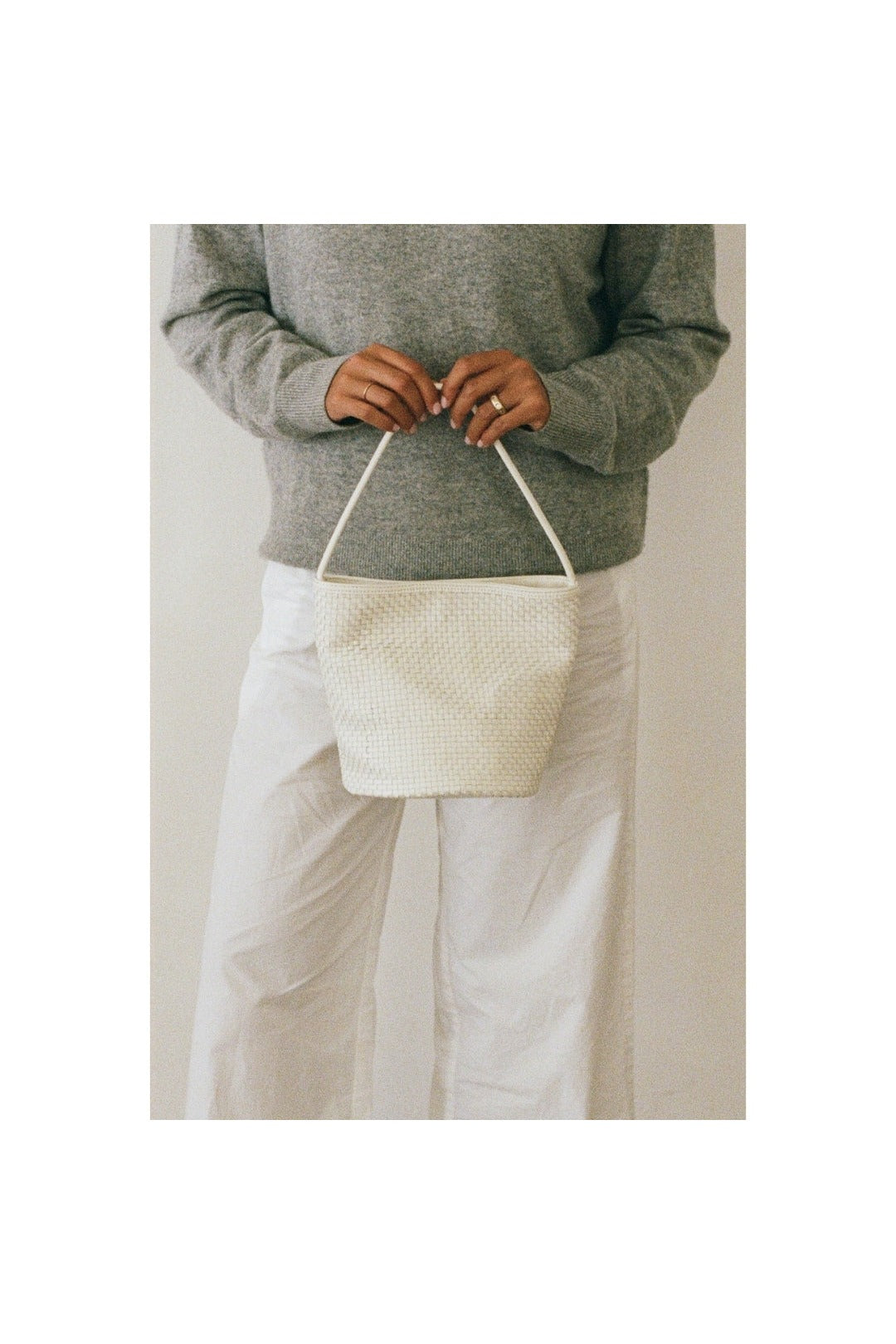 Ivory woven leather bucket bag carried by hand