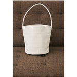 Ivory woven Vancouver bucket bag resting on a brown couch