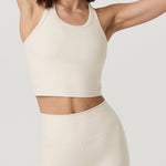 Woman wearing a cream-colored athletic outfit on a plain background