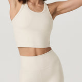 Woman wearing a cream-colored athletic outfit on a plain background