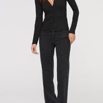 Woman wearing a black long-sleeve top and black pants on a white background