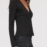 Woman wearing a black long-sleeve top against a white background