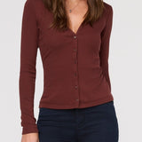 Woman wearing a brown long-sleeve top against a white background