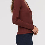 Woman wearing a brown long-sleeve top against a white background