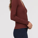 Woman wearing a brown long-sleeve top against a white background