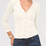Woman wearing a white cardigan and blue jeans on a light gray background