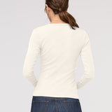 Person wearing a white long-sleeve shirt and blue jeans on a light gray background