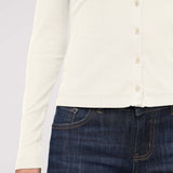 Person wearing a white button-up shirt and dark blue jeans on a light gray background