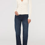 Woman wearing a white cardigan and dark blue jeans on a white background