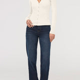 Woman wearing a white cardigan and dark blue jeans on a white background