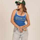 Woman wearing blue ribbed tank top with 'Sorry, I'm On Vacation' text and trucker hat