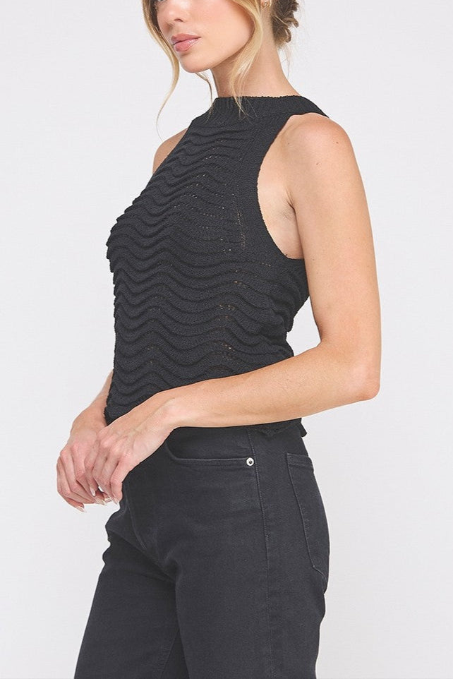Woman wearing a black sleeveless top and black pants on a white background