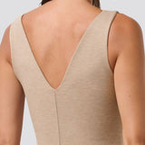 Woman wearing a beige sleeveless top with a V-neckline on a light gray background