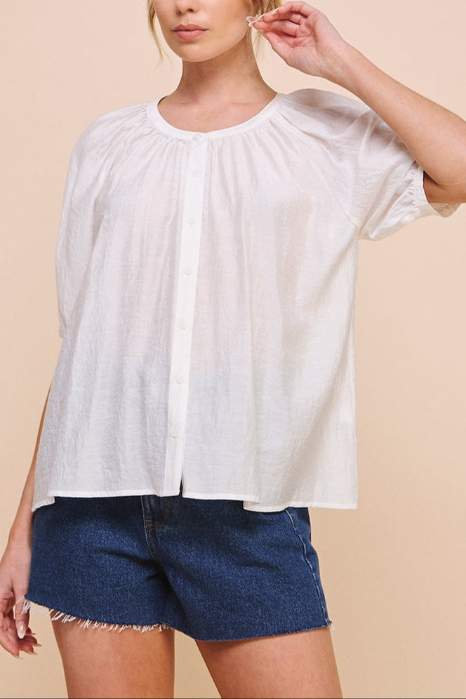 Woman wearing a white blouse and blue shorts against a beige background