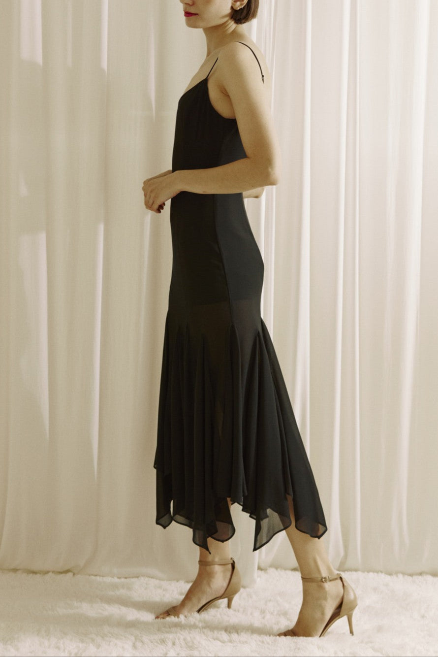 Woman wearing a black dress standing against a white curtain