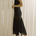 Woman wearing a black dress standing against a white curtain