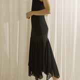 Woman wearing a black dress standing against a white curtain