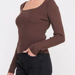 Woman wearing a brown long-sleeve top with a plain background