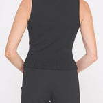 Woman wearing a black sleeveless top and black pants on a white background
