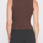 Woman wearing a brown sleeveless top and black pants on a white background