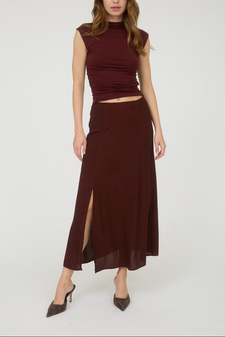 Woman wearing a burgundy top and skirt on a white background