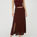 Woman wearing a burgundy top and skirt on a white background