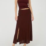 Woman wearing a burgundy top and skirt on a white background