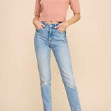 Woman wearing a pink sweater and light blue jeans on a beige background