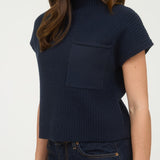 Woman wearing a navy blue ribbed knit top with a pocket on a white background