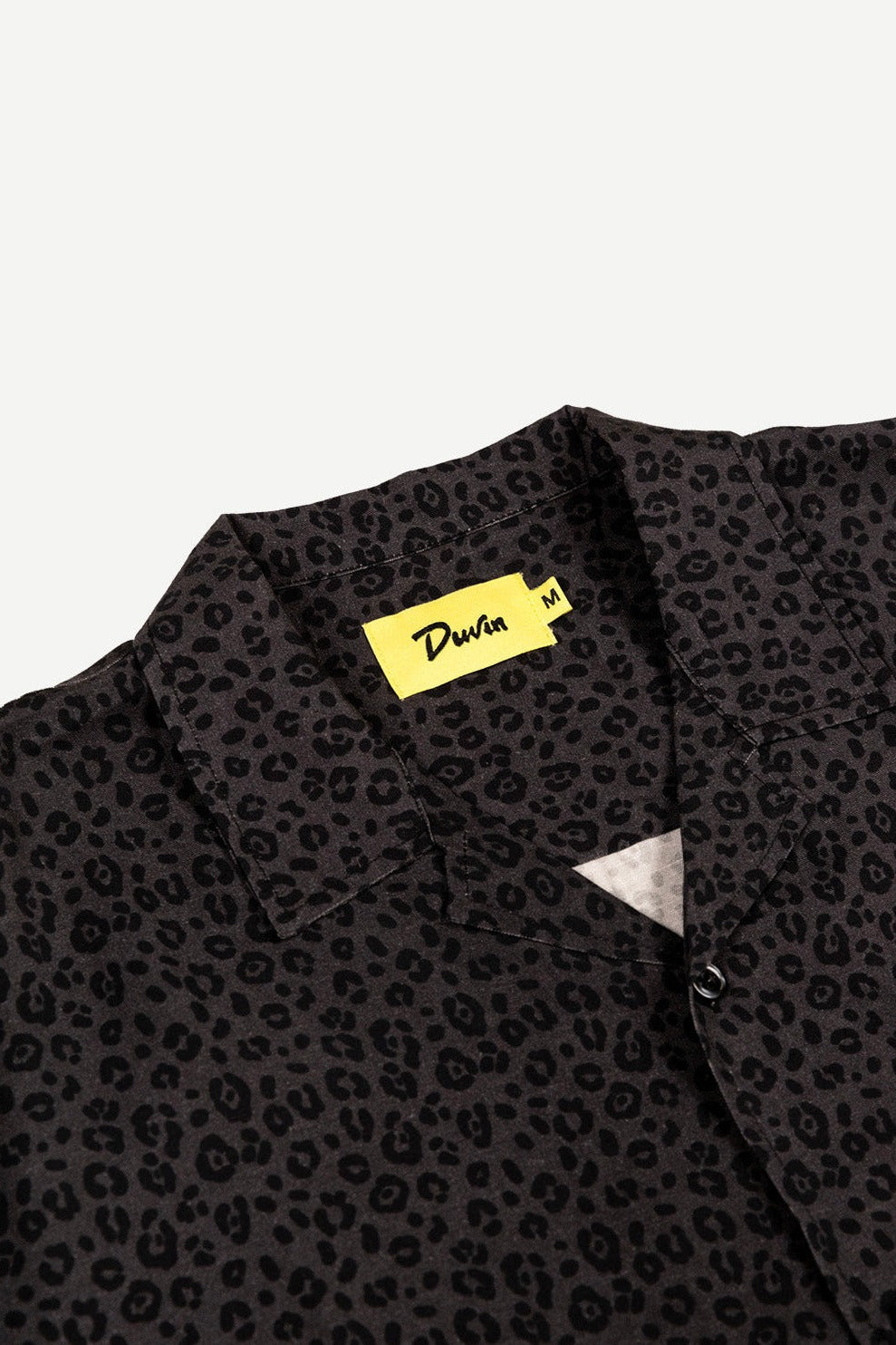 Black patterned shirt with a yellow label on a light gray background