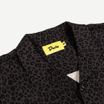 Black patterned shirt with a yellow label on a light gray background
