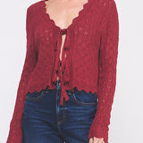 Woman wearing a red knitted cardigan and blue jeans on a white background