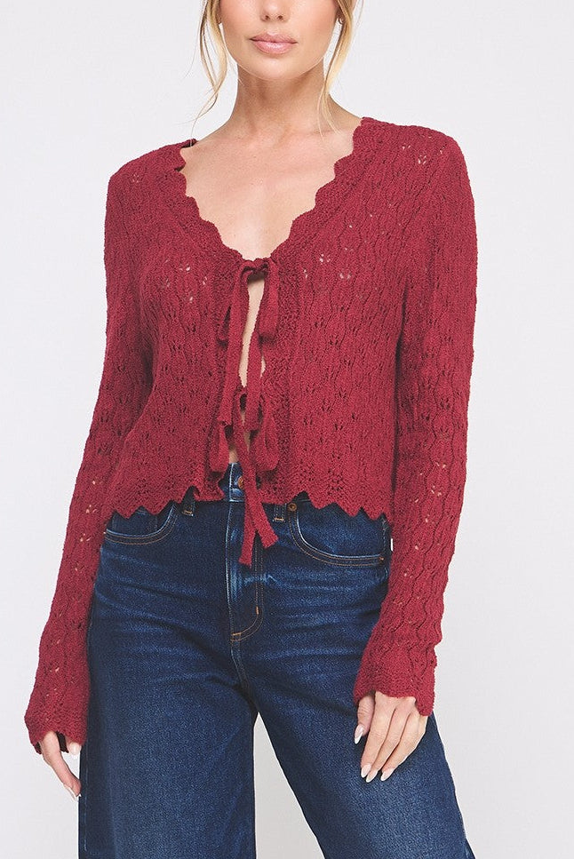 Woman wearing a red knitted cardigan and blue jeans on a white background