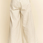 White wide-leg pants with black polka dots on a beige background