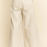 White wide-leg pants with black polka dots on a beige background