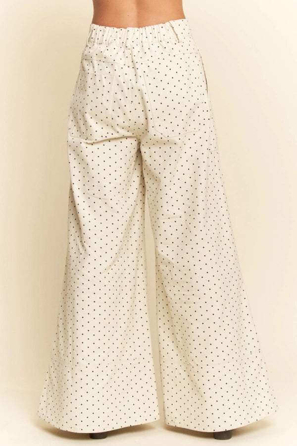 White wide-leg pants with black polka dots on a beige background