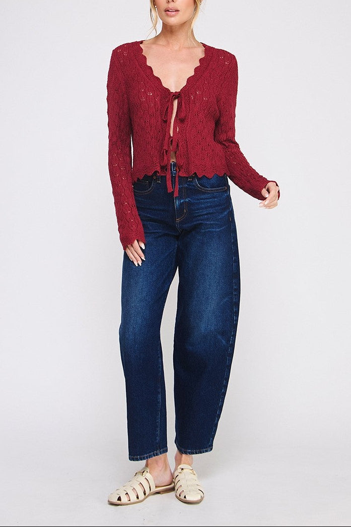 Woman wearing a red cardigan and blue jeans on a white background