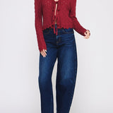 Woman wearing a red cardigan and blue jeans on a white background
