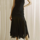 Woman wearing a black slip dress against a white curtain background