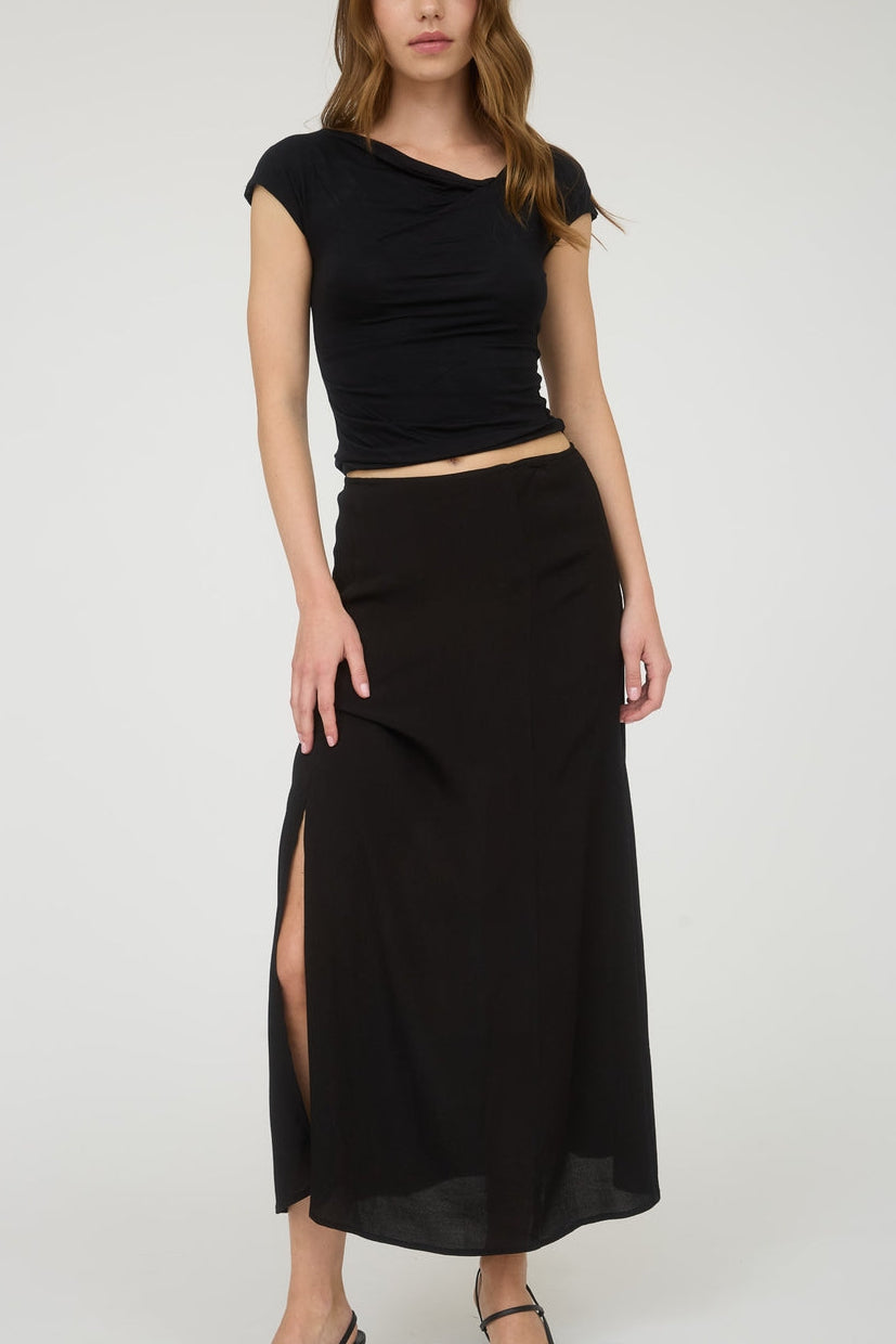 Woman wearing a black top and black skirt with a slit on a white background