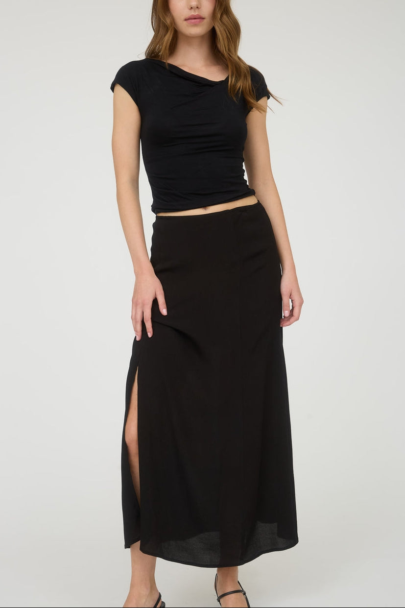 Woman wearing a black top and black skirt with a slit on a white background