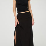 Woman wearing a black top and black skirt with a slit on a white background